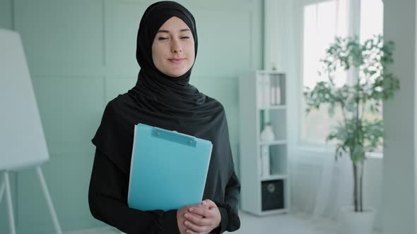 Islamic Indian Lady Muslim Girl Intern Standing at Modern Office Coworking Space Holding Folder with