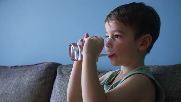 Cute Little Baby Boy Drinking a Glass of Water in Home