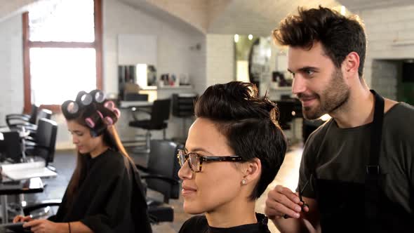 Male hairdresser styling customers hair