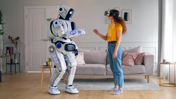 Human-like Robot Is Touching a Hand of a Lady in VR-glasses. Smart Home Concept.