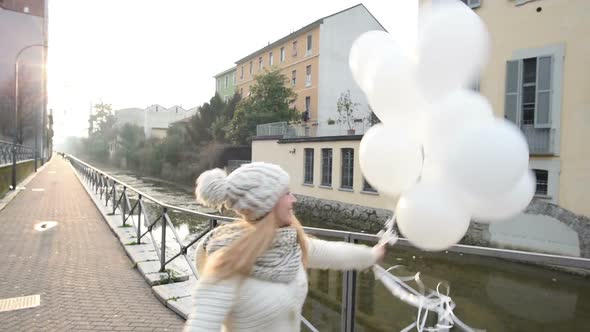 Slow motion young beautiful blonde woman playing with balloons ring around the roses