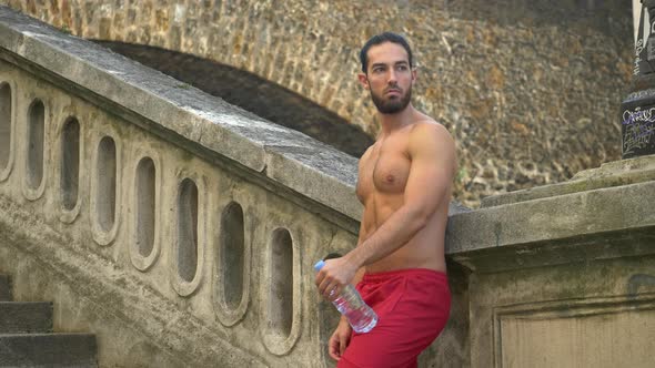 A man takes a break after a workout to drink water.