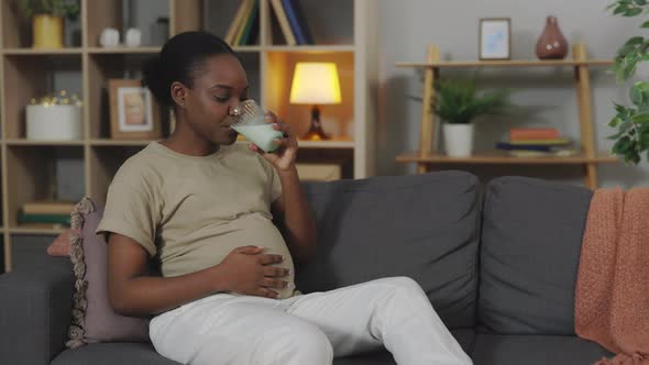 Pregnant Woman Drinking Milk While Sitting on Sofa