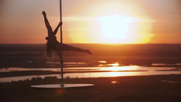 Young Woman with Long Braids Spinning on the Pole and Spreading Her Legs Apart on Sunset