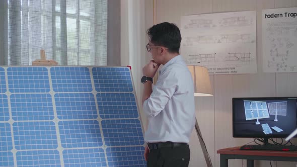 Asian Man Walks Into Looking The Solar Cell In The Room That Has Model Solar Panel Small House