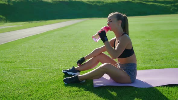 Woman Drinking Water After Training at Stadium