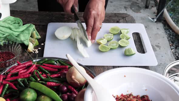 Outdoor Kitchen woman hands with knife slicing onions - colorful ingredients on table