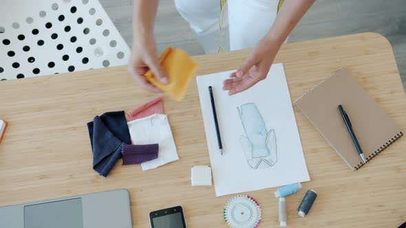 Closeup of Woman Clothes Designer Choosing Fabric for New Garment Looking at Sketch Picture