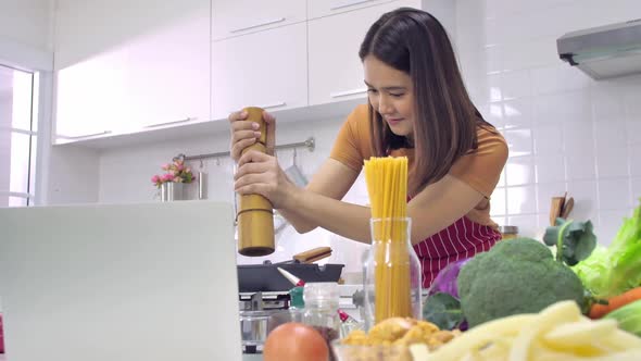 Young Asian woman cooking in kitchen at home. The wife is cooking a special meal for her husband.