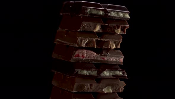 Tower of Pieces Different Chunks of Chocolates Rotate on a Black Background. Strawberry, Mascarpone