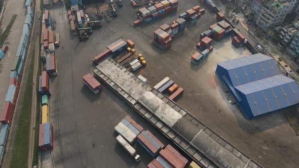 Aerial: inland shipping container terminal with warehouse inside city- drone flight shot