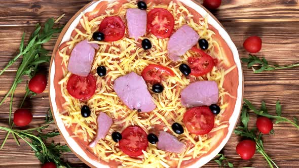 Raw Pizza with tomatoes, olives and ham, Italian style on old wooden table, top view