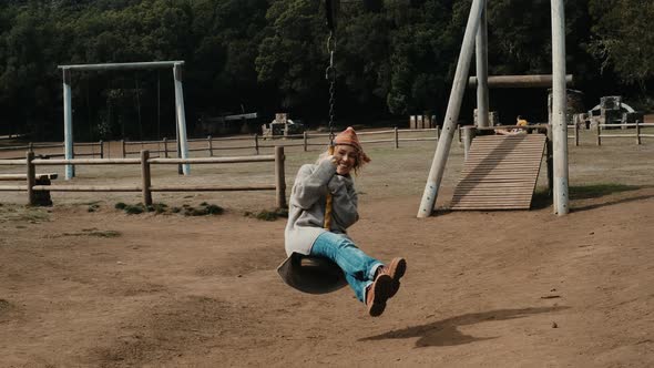 Happy adult mature woman have fun using swing at the nature park. Pretty female people