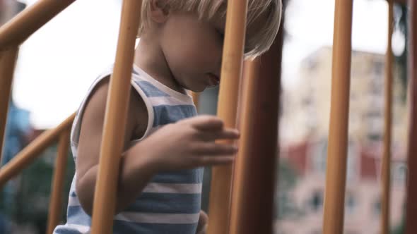 a Small Child Climbs Up the Stairs to the Slide and Rolls Down It