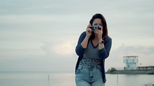 Young Woman Takes Photos on a Retro Camera Outdoors