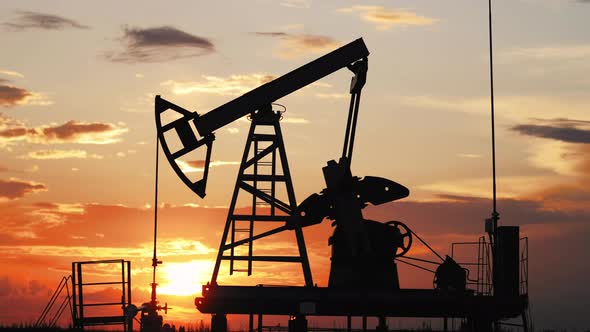 Silhouette Working Oil Pump in Deserted District at Sunset