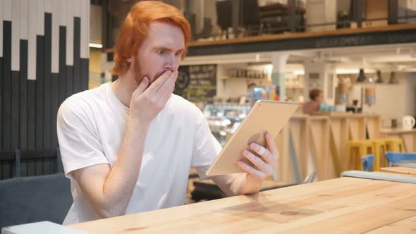 Shocked, Wondering Redhead Beard Man Using Tablet PC in Cafe