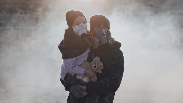 A survivor father carring her daughter in gas mask going through clouds of toxic smoke 