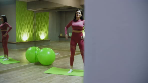 Young Woman in Pink Costume Exercising in the Mirror Fitness Hall