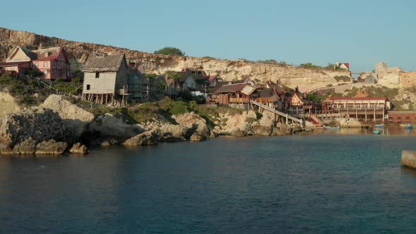 Aerial Establishing Shot of Popeye Village in Anchor Bay, Gozo Island, Malta Wooden Village Houses