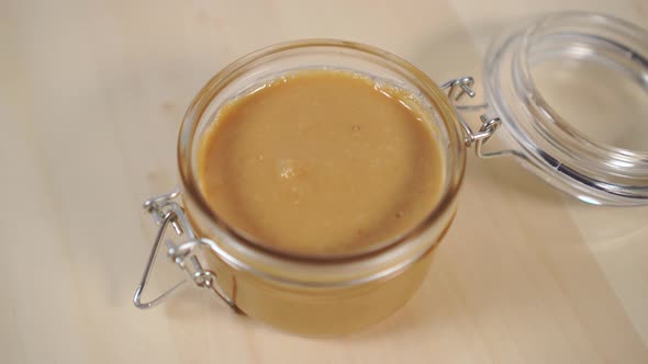 Peanut butter in a glass jar on a wooden table 