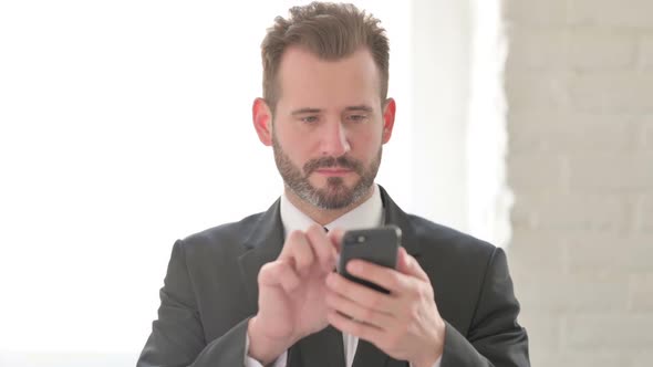 Young Businessman Celebrating Success on Smartphone