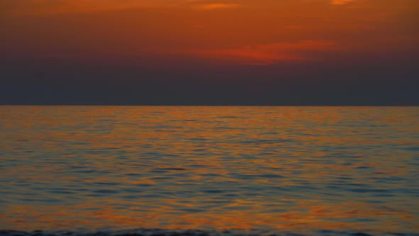 Sunset sky over sea in evening with colorful clouds of orange sunlight.