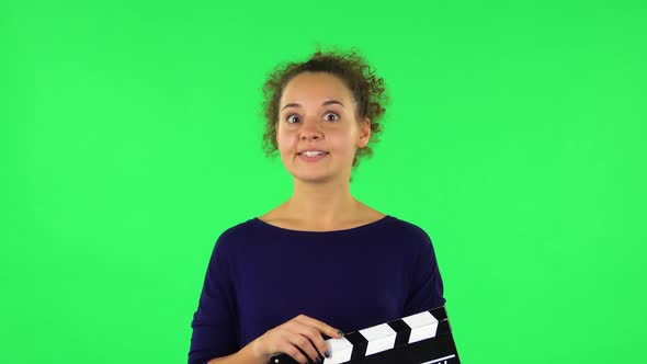 Portrait of Curly Woman Is Holding a Movie in Her Hands. Green Screen