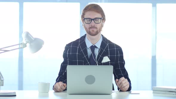 Redhead Businessman Listening Music on Laptop at Work with Closed Eyes