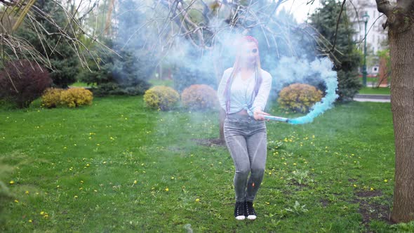 Beautiful Girl in with Multicolored African Braids Posing with Blue Smoke Against the Background of