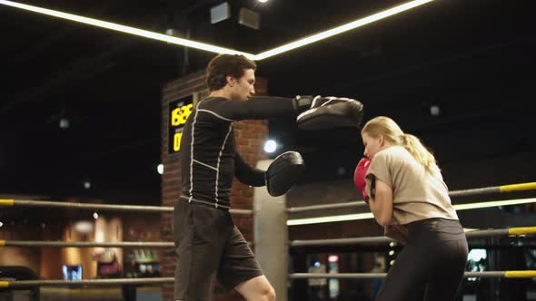 Serious Male Boxer Instructing Female Boxer on Boxing Ring. Sport Couple at Gym