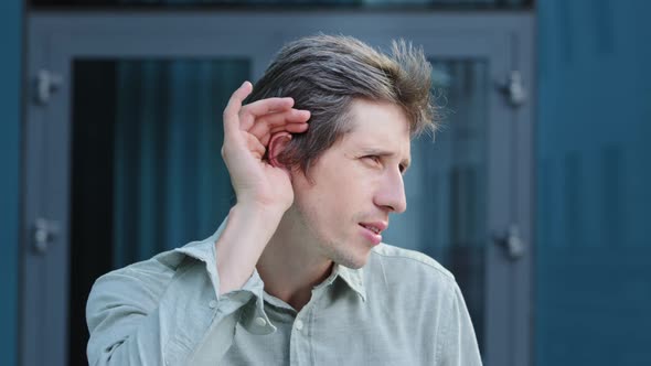 Positive Young Caucasian Male Professional Hold Hand Near Ear Trying to Hear Whisper Something