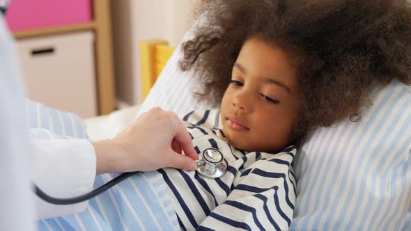 Doctor with Stethoscope and Sick Girl in Bed