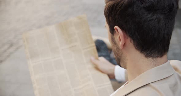 Young Man Sitting On A Bench And Reading An Interesting Article