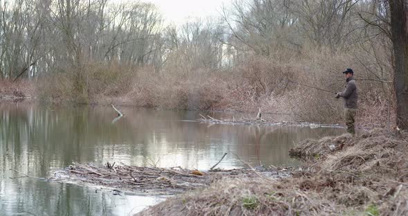 Man Fishing At Lakeshore In Forest