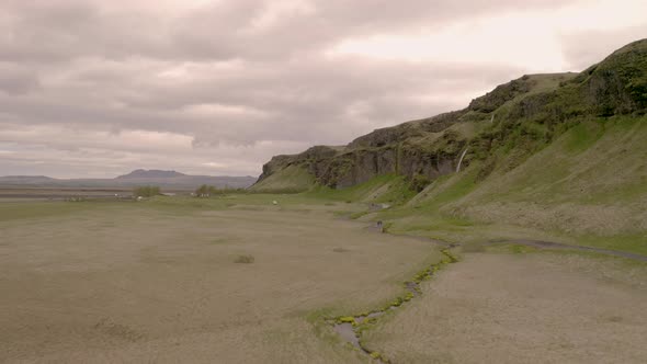 Aerial drone view over people, walking towards the Gljufrabui waterfall, in cloudy Iceland