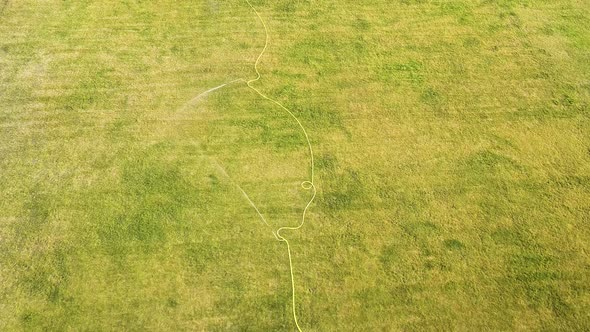 Top down aerial view of football field surface covered with green grass