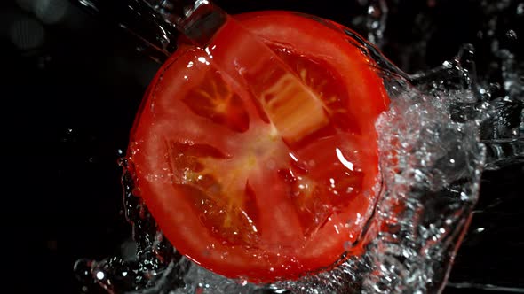 Super Slow Motion Shot of Rotating Tomato Slice and Splashing Water Isolated on Black at 1000Fps