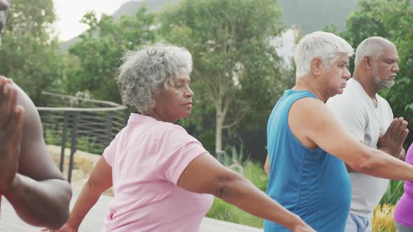 Happy senior diverse people practicing yoga in garden at retirement home