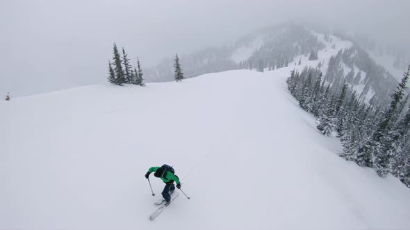 Man Trekking Up Steep Mountain Ski Touring In Winter Storm