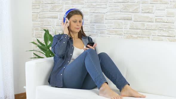 woman dressed in jeans dancing and listening music with headphone