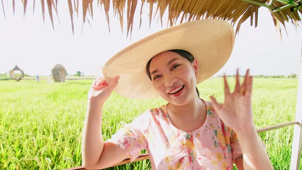 Asian woman making video call showing large rice production field.