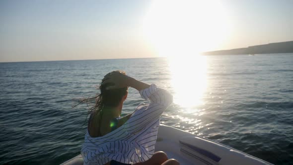 Brunette Woman in a Striped Shirt Floats on the Bow of a Fast Boat