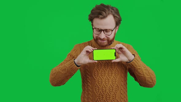 Middleaged Caucasian Entrepreneur Holding Smartphone with Green Screen and Smiling Medium Studio