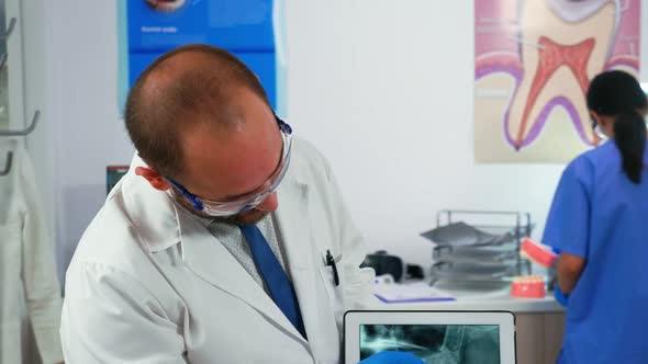 Doctor Holding Tablet with Jaw Xray Showing It to Patient