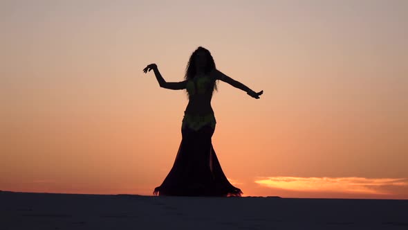 Girl Is Dancing Belly Dancing Against the Beautiful Sunset on the Beach. Silhouettes