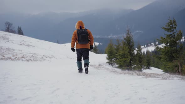 Man Walking Along Path on the Top of Snow Covered Hill