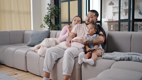 Daughter Discusses Interesting Cartoon with Parents on Couch