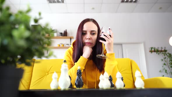 Young Woman Sitting on Yellow Sofa and Playing Chess in Room