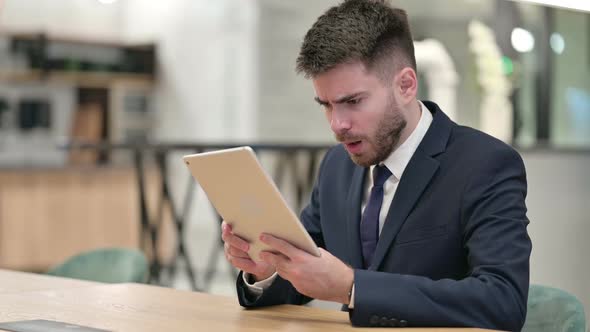 Disappointed Young Businessman Reacting to Loss on Tablet in Office